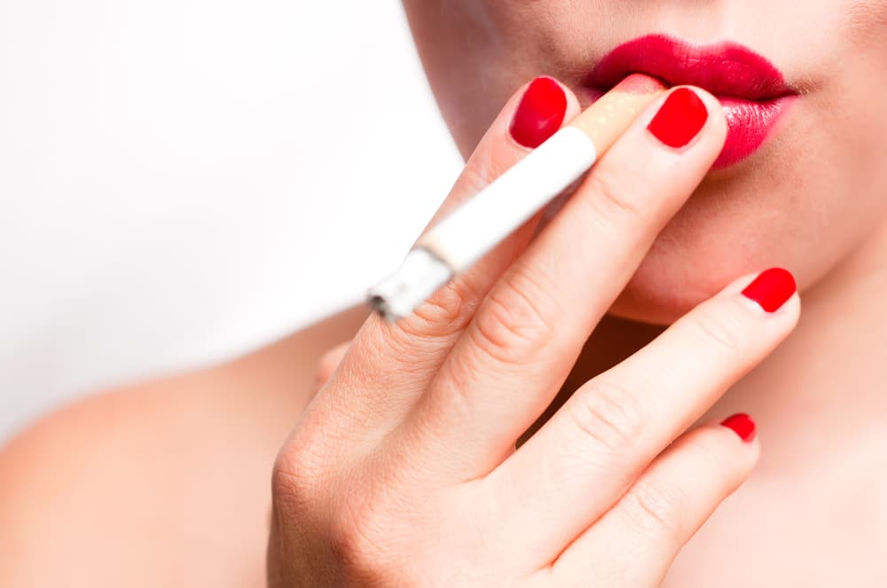 mouth with red lips and red finger nails smoking cigarette