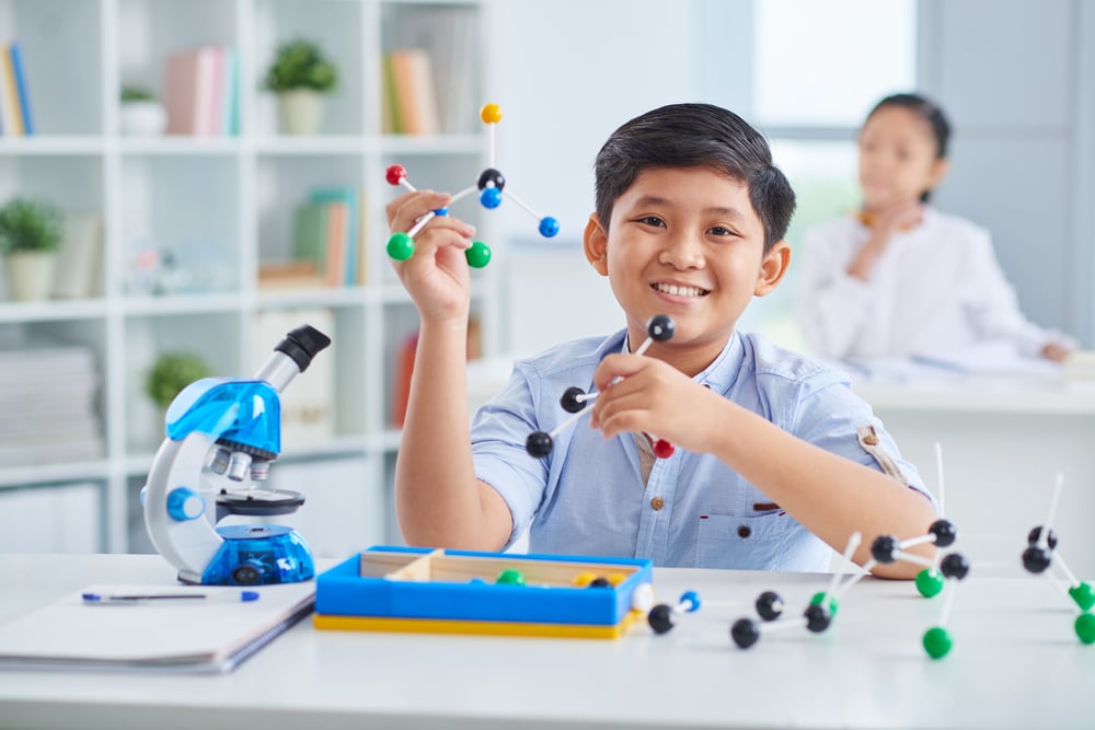 Cheerful Asian boy making molecular model in class